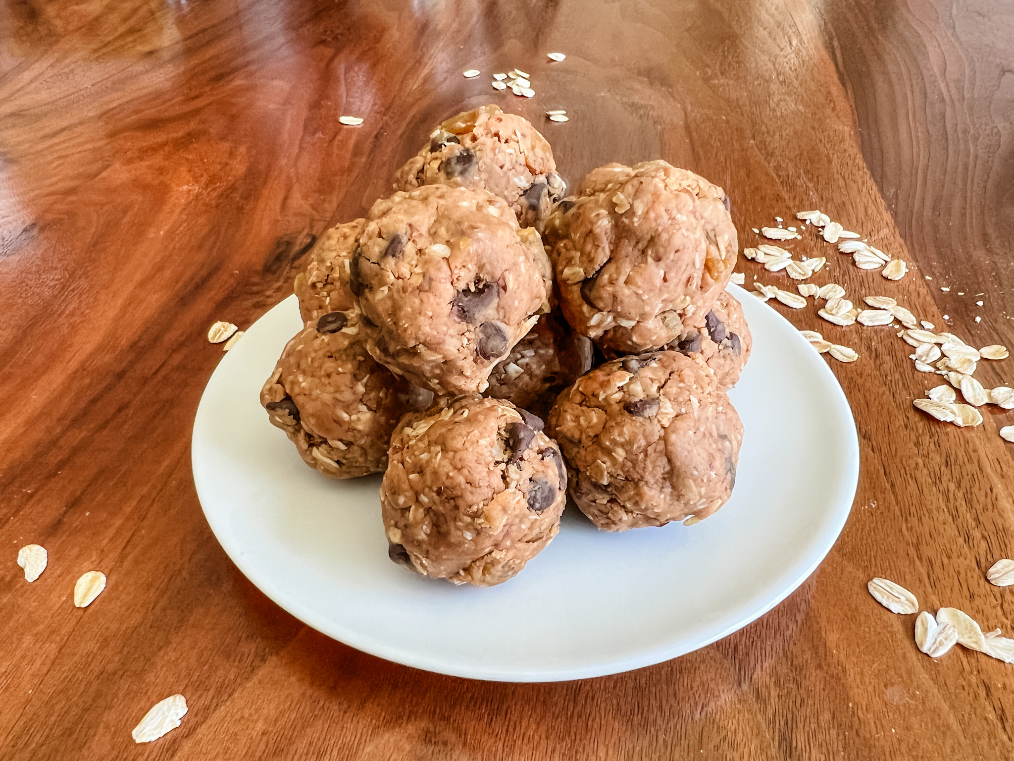 sunbutter energy bites stacked on a white plate sitting on a wooden table