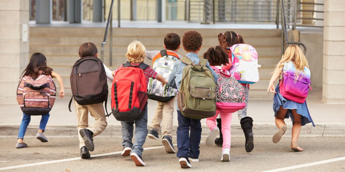 children with backpacks running to class