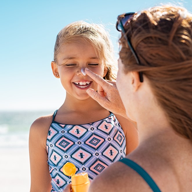 woman putting sunscreen on girl