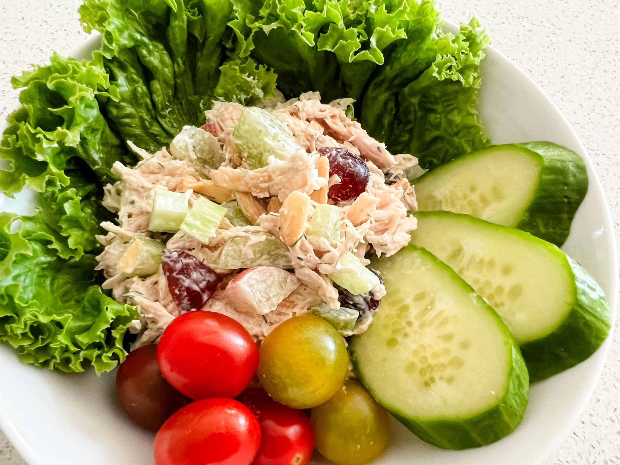 Bowlofchickensaladwithlettucecherrytomatoesandslicedcucumbers