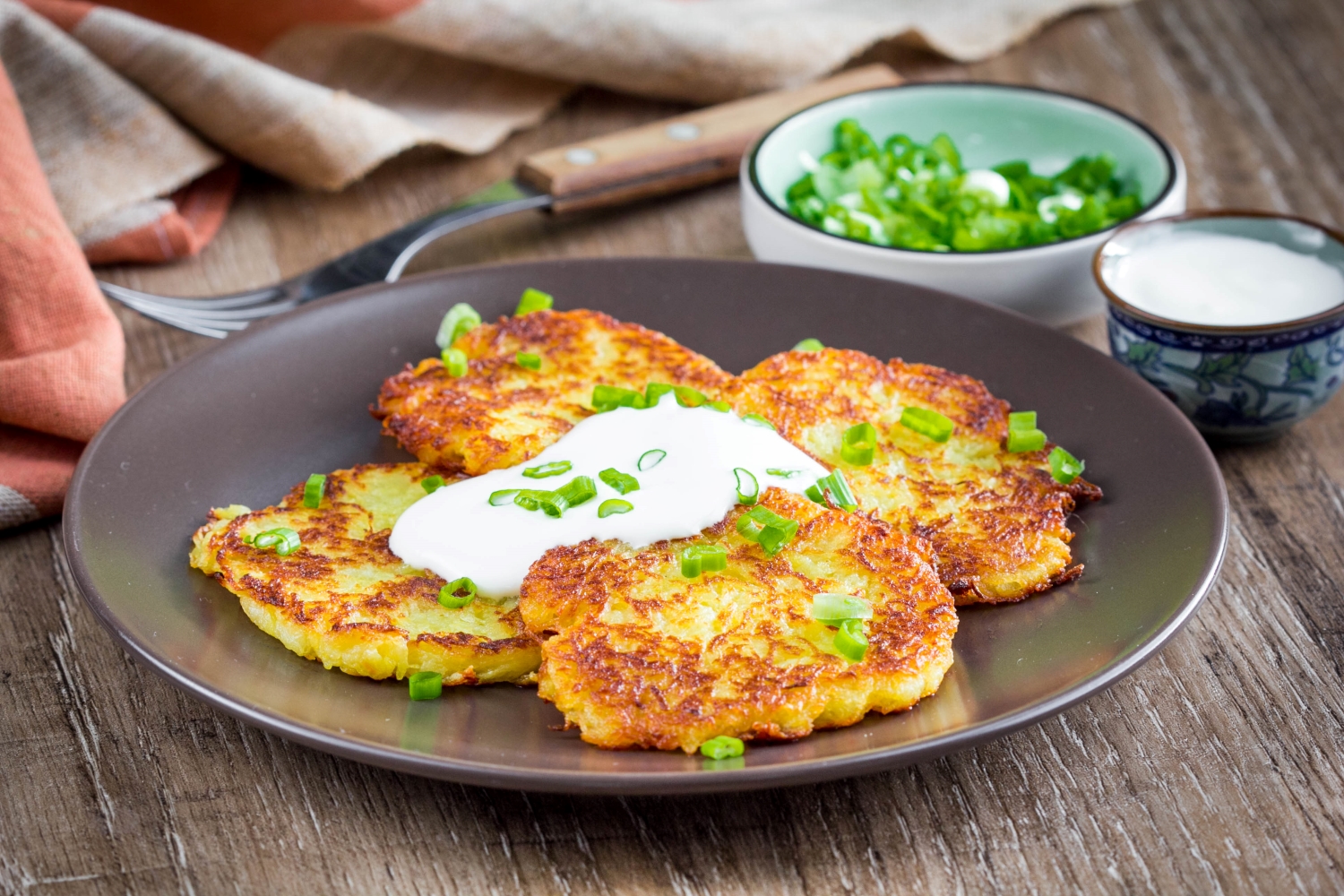 a plate of Air Fryer Apple Potato Latkes served with Greek yogurt and sliced scallions